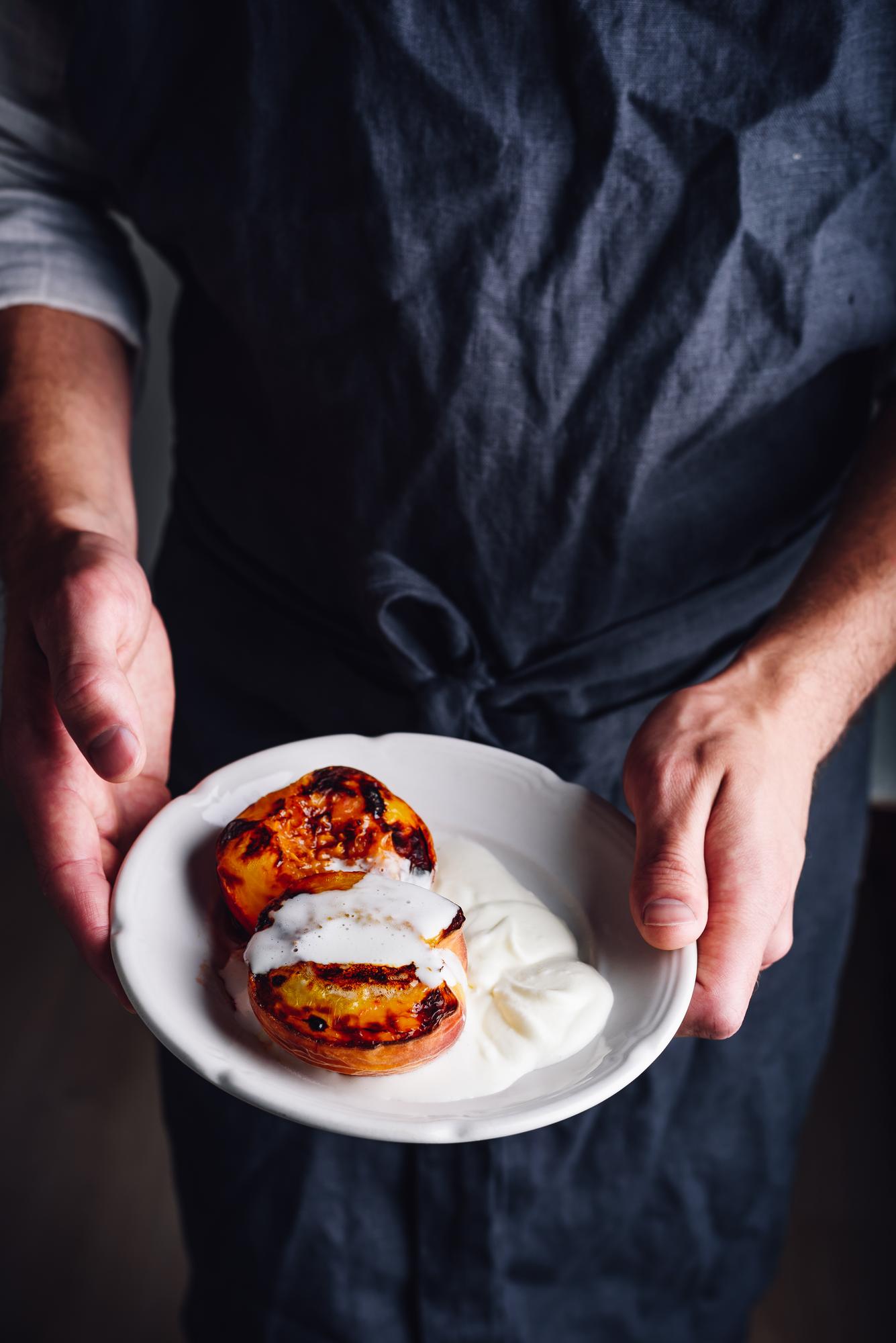 Chef plating a delicate dish on a dark plate